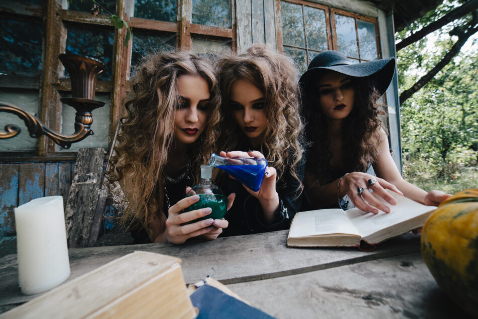 Tres brujas realizan un ritual mágico, sentadas a la mesa, con el elixir en la mano, en la víspera de Halloween.